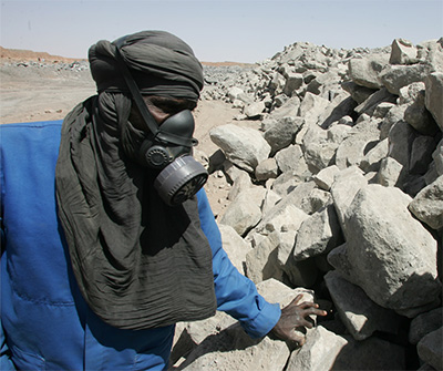 Un employé de la mine d'uranium à ciel ouvert de Arlit, dans le désert de l'Aïr (Niger), inspecte de la roche contenant de l'uranium, le 23 février 2005. PIERRE VERDY / AFP